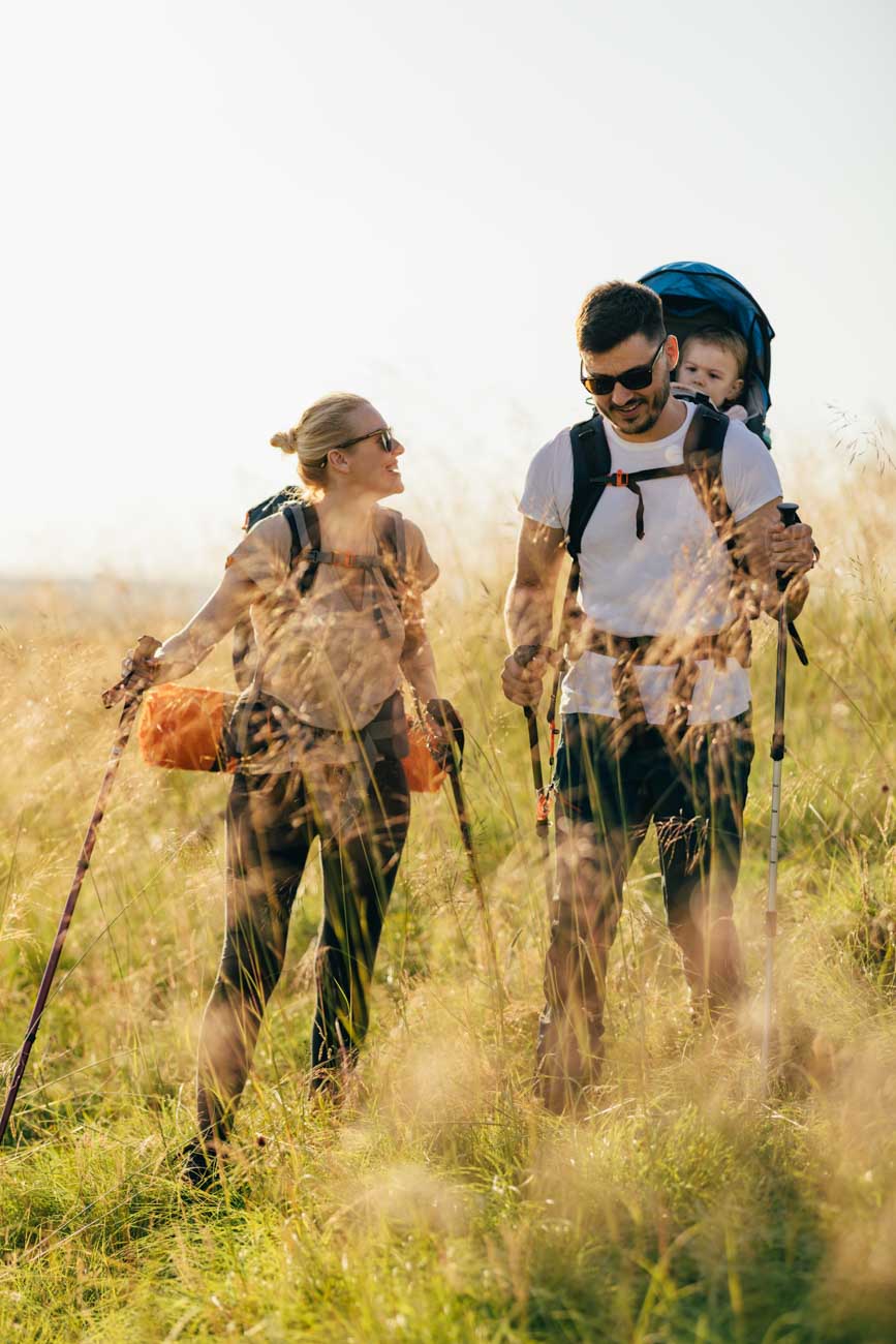 Happy Family With One Child Hiking Over Grass Fields Happy Family With One Child Hiking Over Grass Fields